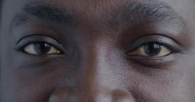 Afrika kökenli Amerikalı erkeklerin kameraya neşeyle bakan gözlerinin yavaş çekim portresi. İnsan vücudu ve mutluluk ifadesi konsepti.