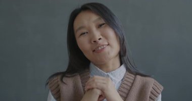 Siyah arka planda kameraya bakan Asyalı genç bir kadının portresi. Çevrimiçi video arama ve vlog tutma kavramı.