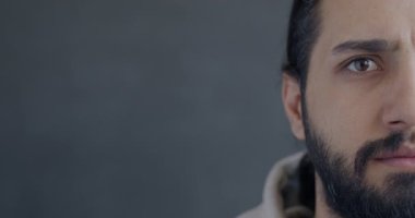 Gri arka planda kameraya bakan endişeli Orta Doğulu yarım yüzlü adamın yakın plan portresi. Olumsuz duygu ve insan kavramı.