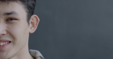 Gri arka planda kameraya bakıp gülen neşeli Asyalı bir adamın yakın plan portresi. İnsanlar ve iyi ruh hali kavramı.