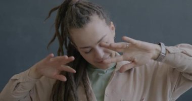 Rasta giymiş, siyah arka planda dans eden neşeli genç bir kadının yavaş çekim portresi. İnsanlar ve eğlence konsepti.