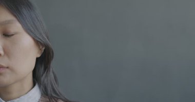Üzgün ve yalnız hissederek kameraya bakan mutsuz Asyalı kadının yavaş çekim portresi. Olumsuz duygu ve insan kavramı.