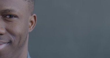 Siyah arka planda kameraya bakıp gülümseyen neşeli Afrikalı Amerikalı adamın yavaş çekim portresi..