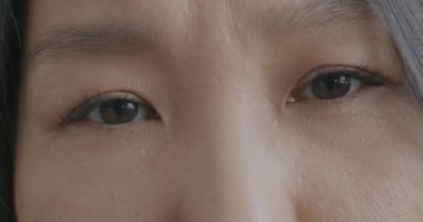 Üzgün Asyalı kadınların endişeli ve endişeli bakışlarının yavaş çekimde çekilmiş bir portresi. Yüz ifadesi ve olumsuz duygu kavramı.