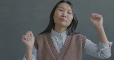 Siyah arka planda kameraya bakan Asyalı genç bir kadının yavaş çekim portresi. Mutlu insanlar ve eğlence konsepti.