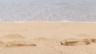 Sahildeki ıslak kumda deniz dalgalarının ayak izlerinin üzerinde yuvarlandığı görüntüler. Barselona, Katalonya, İspanya 'da Akdeniz ve Barceloneta sahilleri