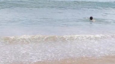 Yakışıklı, uzun saçlı genç sıcak bir yaz gününde denizde yüzer. Dostane yaz konsepti, sağlıklı yaşam tarzı konsepti, yaz tatili.