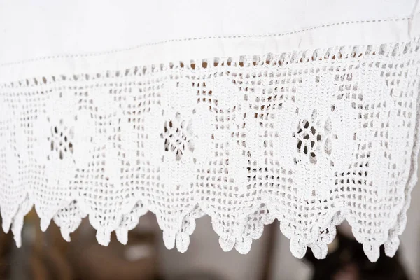 Handmade crochet blanket made of organic cotton. White original crochet lace. Beautiful, thin, white knitted lace textile close-up