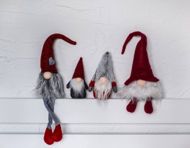 Elf Noel süsleri. Kırmızı şapkalı dört cüce ahşap bir rafta oturuyor. Noel ve Yeni Yıl konsepti, tebrik kartı