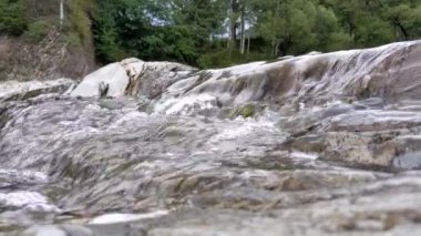 Mountain river with cold clear water. The river flows over the stones with little waterfall