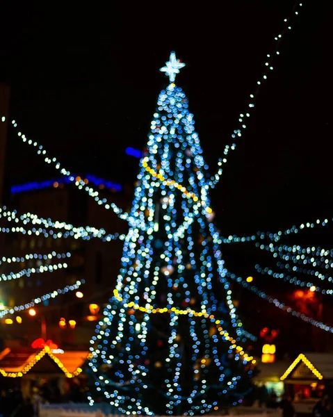 stock image Bokeh silhouette of Christmas tree. Christmas tree with decorations and lights bokeh in a black background, outdoor