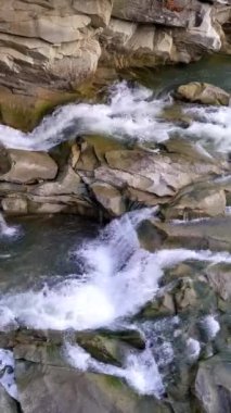 Mountain river with cold clear water. The river flows over the stones with little waterfall