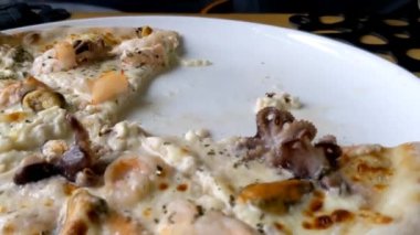 Lezzetli deniz ürünleri pizzası. Adam pizzayı kesiyor. Bir restoranda öğle yemeği.