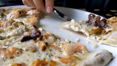 Lezzetli deniz ürünleri pizzası. Adam pizzayı kesiyor. Bir restoranda öğle yemeği.