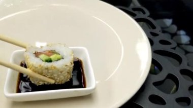 Çubukları kullanarak siyah tahta tahtadan bir suşi rulosu al ve yaklaş. Japon yemekleri yeme konsepti