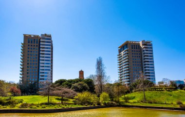A beautiful mixed park with palm trees and a small pond next to a high-rise modern residential area in Barcelona, Catalonia, Spain