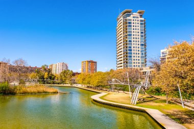 A beautiful mixed park with palm trees and a small pond next to a high-rise modern residential area in Barcelona, Catalonia, Spain