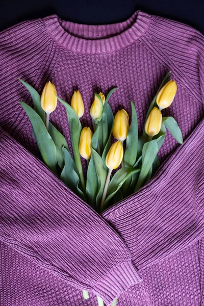 International Women's Day, March 8, birthday, Valentine's day concept. Wool sweater hugging yellow tulips. Top view. Cozy spring concept