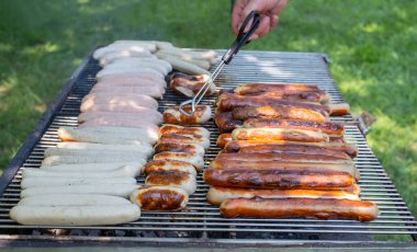 Izgara sosisler ızgarada kızartılıyor, açık havada. Barbekü. Izgarada kızartılmış ve ızgarada tütsülenmiş yiyecekler.