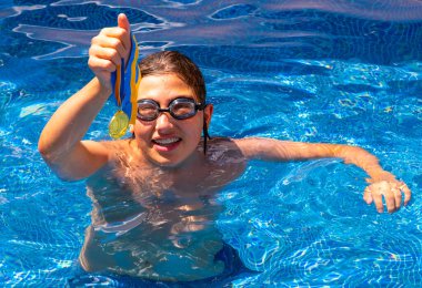 Successful caucasian young swimmer with award in outdoor pool. Golden trophy in swimming, teen boy showing off medal. Healthy lifestyle concept, sport activities