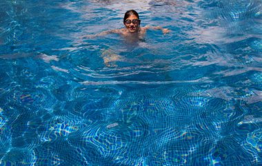 Cute boy in a swimming pool. Sport activities for children, outdoor swimming lessons. Summer vacation at the hotel. Outdoor swimming pool. Healthy lifestyle concept