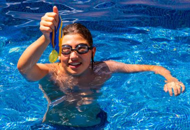 Successful caucasian young swimmer with award in outdoor pool. Golden trophy in swimming, teen boy showing off medal. Healthy lifestyle concept, sport activities