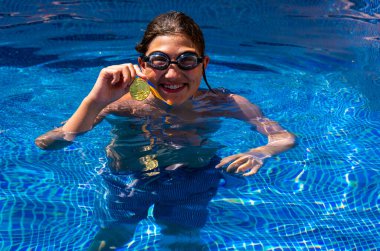 Successful caucasian young swimmer with award in outdoor pool. Golden trophy in swimming, teen boy showing off medal. Healthy lifestyle concept, sport activities