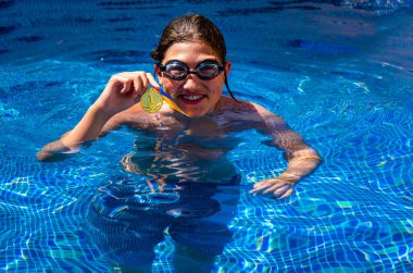 Successful caucasian young swimmer with award in outdoor pool. Golden trophy in swimming, teen boy showing off medal. Healthy lifestyle concept, sport activities
