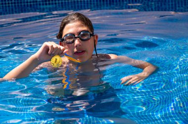 Successful caucasian young swimmer with award in outdoor pool. Golden trophy in swimming, teen boy showing off medal. Healthy lifestyle concept, sport activities