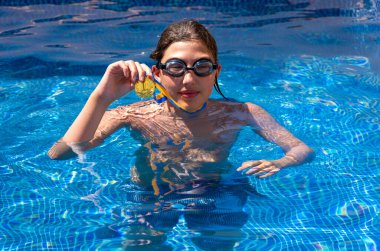 Successful caucasian young swimmer with award in outdoor pool. Golden trophy in swimming, teen boy showing off medal. Healthy lifestyle concept, sport activities
