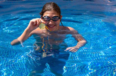 Successful caucasian young swimmer with award in outdoor pool. Golden trophy in swimming, teen boy showing off medal. Healthy lifestyle concept, sport activities