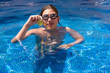 Successful caucasian young swimmer with award in outdoor pool. Golden trophy in swimming, teen boy showing off medal. Healthy lifestyle concept, sport activities