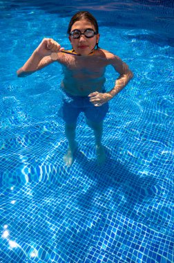 Successful caucasian young swimmer with award in outdoor pool. Golden trophy in swimming, teen boy showing off medal. Healthy lifestyle concept, sport activities