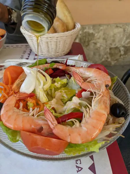 Deniz ürünleri ve taze sebzelerle dolu bir tabağın dikey görüntüsü.