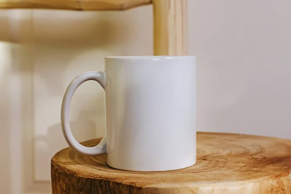 White mug mock-up. Cup standing on the wooden table close-up