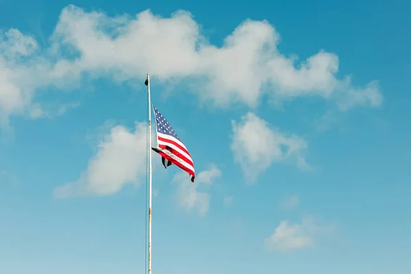 National flag of the United States of America waving over the blue sky with a little clouds