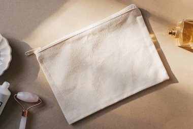 Bej renkli, krem arkaplanda boş bir makyaj çantası modeli. Doğal güneş ışığı
