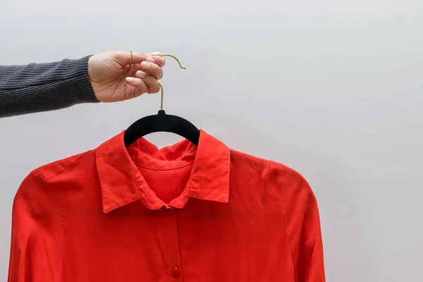 女用手托着挂着红衣服的衣架 挂在白墙上 个人造型师 — 图库照片