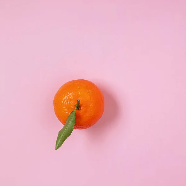 stock image Mandarin, orange with a leaf isolated on pink background