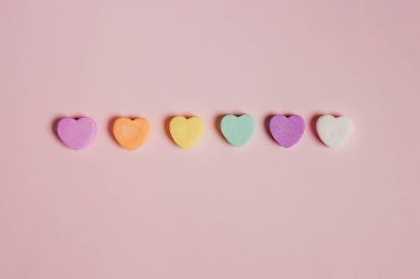 Rainbow colored heart shaped candies on pastel pink background, Valentine's day concept