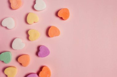Colorful heart shaped sugar candies on pastel pink background, Valentine's day backdrop
