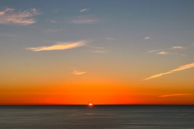 Sun going over the horizon right into the ocean, beautiful sunset background