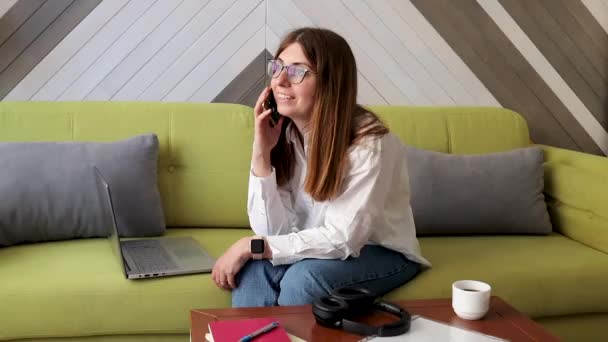 Ung Kvinna Svara Telefonsamtal Medan Arbetar Vardagsrummet Modern Livsstil — Stockvideo