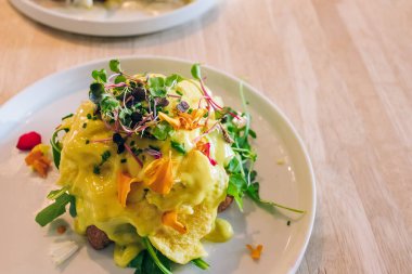 Close-up view of the delicious eggs benedict on the plate, decorated with micro green