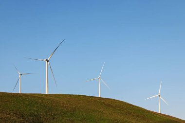Wind power turbines on the green hill over the blue sky. Sustainable energy