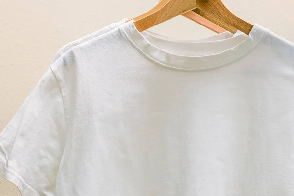 White cotton t-shirts on the hangers close-up. Place for text