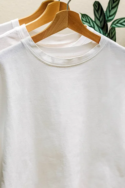 White cotton t-shirts on the hangers close-up. Place for text