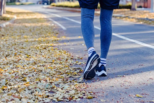 男足在训练员中的特写将在街上跑来跑去 地上长满黄叶 秋季室外跑步 — 图库照片