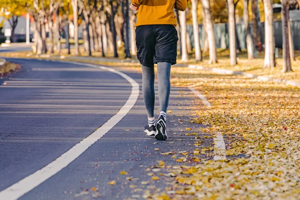 一个无法辨认的人从后面向户外慢跑 从后面看去 街上的黄叶 秋天的长跑 — 图库照片