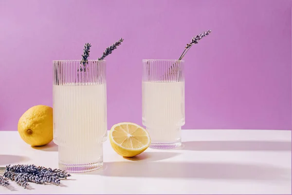 stock image Two ribbed glasses with lavender lemonade over purple background, summer refreshing drink